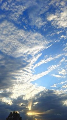 the sun is shining through the clouds in the sky above some grass and trees on the other side