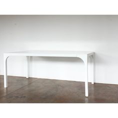 a white table against a white wall in an empty room