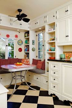 a kitchen with black and white checkered flooring, an oven, cabinets, counter top, and dining table