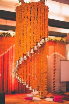 an arrangement of orange flowers hanging from the ceiling in front of a stage with lights