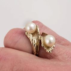 "This 18K yellow gold ring has a distinctive bypass design with two beautiful pearls. The naturalistic ring conveys the feel of coral or foliage, with a textured surface that hugs the pearls. This vintage statement ring will graze the knuckle on most women. Vintage: 1970s Size: 5 1/4 Materials: 18K Yellow Gold, Cultured Pearls Marked: 18K 2 Cultured Pearls: approx. 7mm Width North to South: 1\" Stands Off Finger: 3/8\" Shank Width: 1/8\" Weight: 5.2 dwt / 8.5 g / .26 ozt Condition: Very Good FRE Unique Yellow Gold Pearl Ring For Anniversary, Naturalistic Design, Bypass Ring, 18k Yellow Gold Ring, Yellow Gold Ring, Pearl Size, Saint Louis, Women Vintage, Pearl Ring