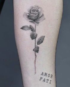 a black and white rose tattoo on the right arm with words below it that read, amor fati