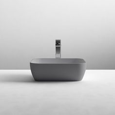 a modern bathroom sink sitting on top of a white counter next to a gray wall