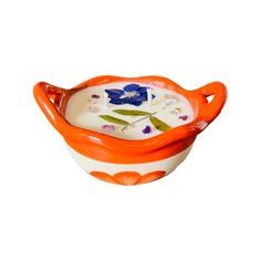 an orange and white bowl with blue flowers on the inside is sitting in front of a white background