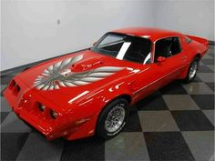 a red car is parked in a room with black and white checkered flooring