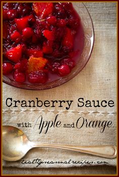 cranberry sauce with apple and orange in a glass bowl next to a spoon