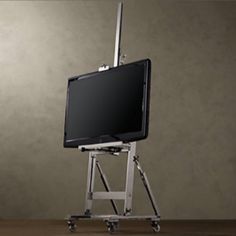 a flat screen tv sitting on top of a metal stand with wheels and casters