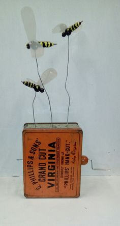 a tin can with three bees in it sitting on top of a white table next to a wall