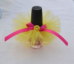 a small bottle with a smiley face on it and a pink ribbon around the top