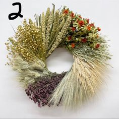 a wreath made out of dried flowers and grass with the letter s in the middle