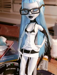 a doll with blue hair and glasses is posed