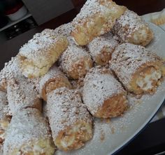 a white plate topped with lots of powdered sugar covered pastries on top of a table