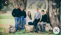 a group of people standing next to each other in front of two large tree trunks