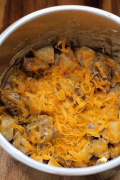 a pot filled with cheese and meat on top of a wooden table