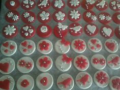 red and white cupcakes decorated with hearts, flowers, and other decorative items