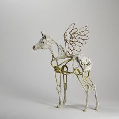 a metal horse with wings on it's head and tail is standing in front of a white background