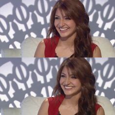 a woman sitting in a chair with long hair and wearing a red top smiling at the camera