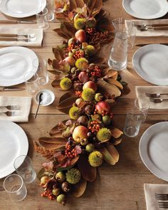 a long table with plates and silverware on it, decorated in autumn foliages