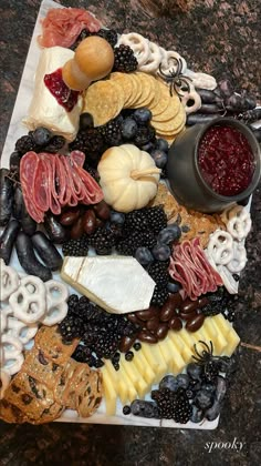 an assortment of cheeses, crackers, and fruit arranged on a platter