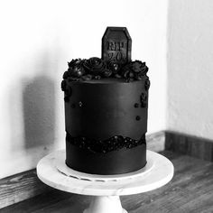 a black and white photo of a decorated cake on a pedestal with a tombstone in the middle