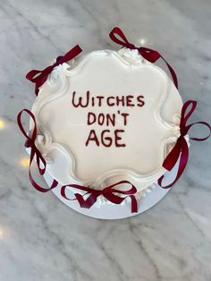 a cake with writing on it that says witches don't age and red ribbon around the edges