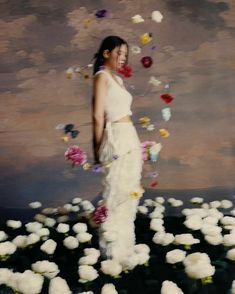 a woman in white dress surrounded by flowers