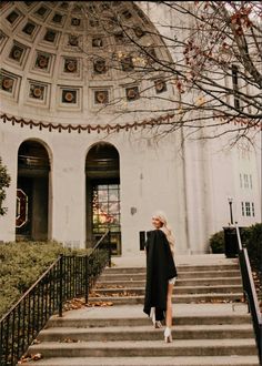 a woman is walking down some steps in front of a building