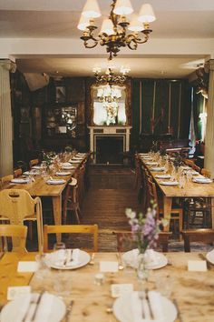 an empty dining room with wooden tables and yellow chairs in front of a fire place