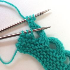 two crochet hooks are sitting next to each other on a white surface with green yarn