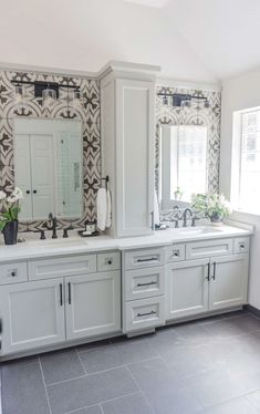 a bathroom with two sinks and mirrors on the wall next to each other in front of a window