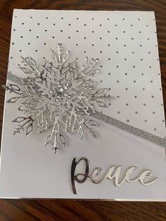 a christmas card with a snowflake on the front and peace in the middle