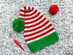 a red and green knitted hat next to a crochet pom - pom