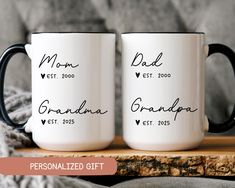 two personalized coffee mugs sitting on top of a wooden table next to a blanket