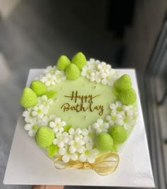 a birthday cake with white flowers and green frosting