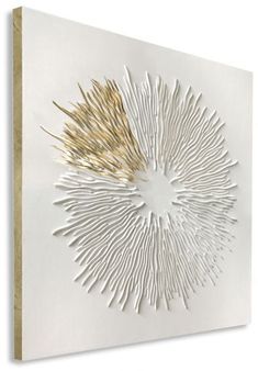 a white and gold art piece on the wall with an abstract design in it's center