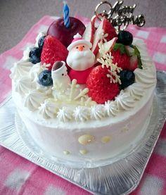 a white cake topped with fruit and a santa clause decoration