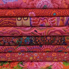 a stack of colorful fabrics with different patterns and colors on the fabric, including flowers