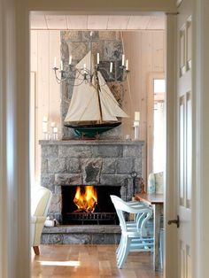 a living room with a fire place and a sailboat on the fireplace mantel