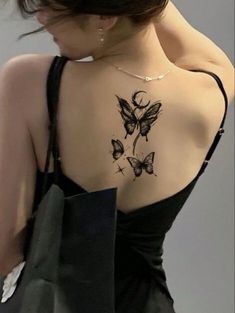 a woman with a tattoo on her back holding a shopping bag and wearing a black dress