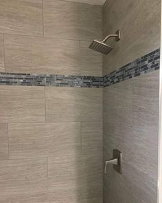 a bathroom with a shower head and tiled walls