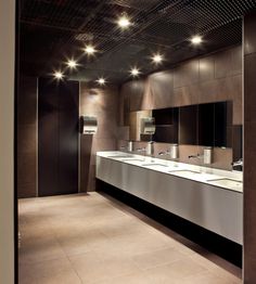 a public restroom with sinks and mirrors on the wall, lights above them are dimming