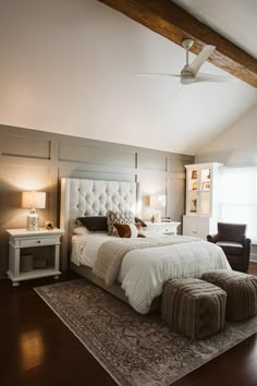 a bedroom with a bed, ottoman and ceiling fan