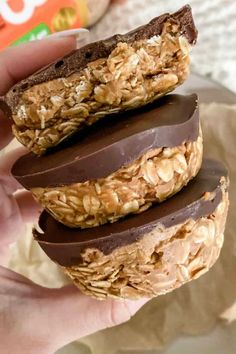 a person holding three chocolate covered cookies in their left hand and one with oatmeal on top