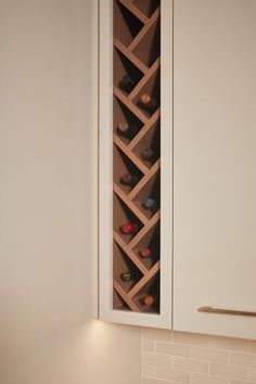 a wine rack in the corner of a white cabinet next to a wall mounted sink