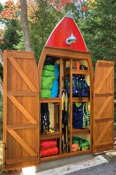 an outdoor storage area with wooden doors and umbrellas on it's sides, filled with various items