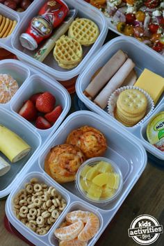 several plastic containers filled with food on top of a wooden table next to fruit and crackers