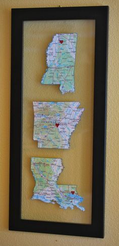 three maps are mounted on a wall in a black frame with a red heart at the bottom