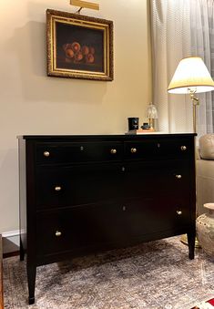 a black dresser sitting next to a lamp in a living room