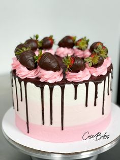 a white and pink cake with chocolate covered strawberries