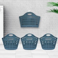 three blue laundry baskets next to a white brick wall